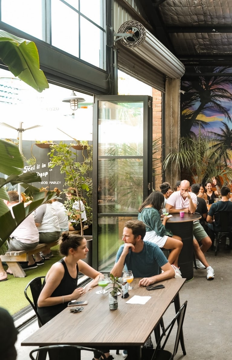 A crowd of people sitting around long tables in a brewery with a colourful mural. at One Drop Brewing, Botany, Sydney, New South Wales © One Drop Brewing Co. A crowd of people sitting around long tables in a brewery with a colourful mural. at One Drop Brewing, Botany, Sydney, New South Wales © One Drop Brewing Co.