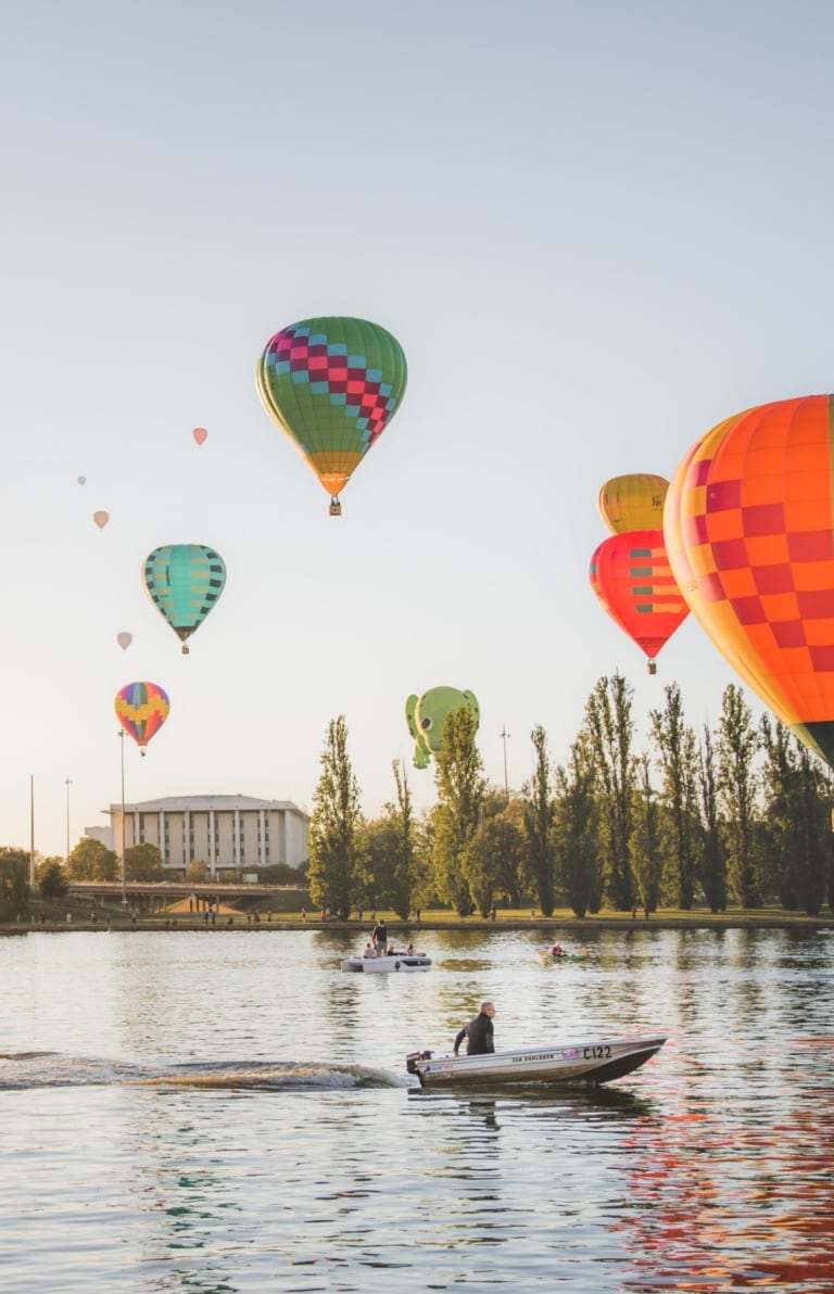 Montgolfières survolant les eaux paisibles du Lake Burley Griffin sur lequel voguent des bateaux à Canberra, Territoire de la Capitale Australienne © EventsACT Montgolfières survolant les eaux paisibles du Lake Burley Griffin sur lequel voguent des bateaux à Canberra, Territoire de la Capitale Australienne © EventsACT
