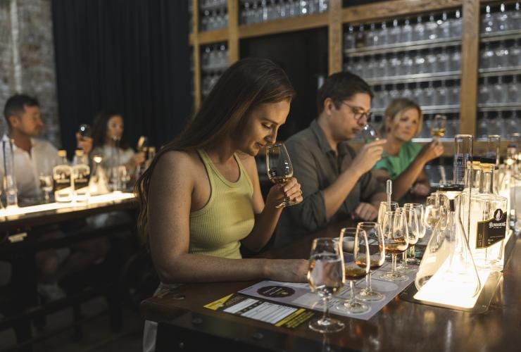 Eine Gruppe sitzender Personen, die während der Bundaberg Rum Experience verschiedene Spirituosen durch Riechen und Schmecken verkosten, Bundaberg, Queensland © Tourism and Events Queensland