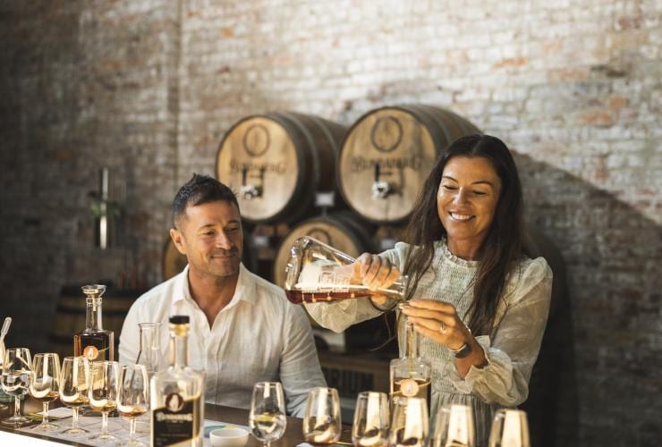 Ein Mann und eine Frau, die Rum in Gläser gießt, Bundaberg Rum Distillery, Bundaberg, Queensland © Tourism and Events Queensland