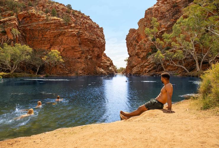 A man sits on the sand near Ellery Creek Big Hole, West MacDonnell Ranges, Northern Territory © Tourism Australia