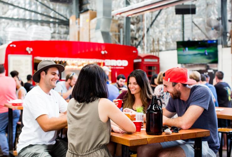 A group of friends gathered around a table at Capital Brewing Co and Brodburger, Canberra, Australian Capital Territory © Kara Rosenlund for VisitCanberra