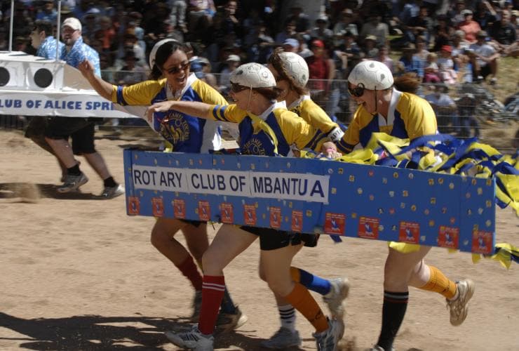 A team of people wearing a boat made of cardboard race at the Henley on Todd Regatta, Alice Springs, Northern Territory © Henley on Todd Inc