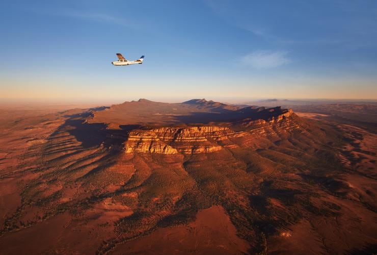 A small plane soaring over a large, mountainous outback structure, Bush Pilots Scenic Flight, Wilpena Pound, Flinders Ranges National Park, South Australia © Adam Bruzzone