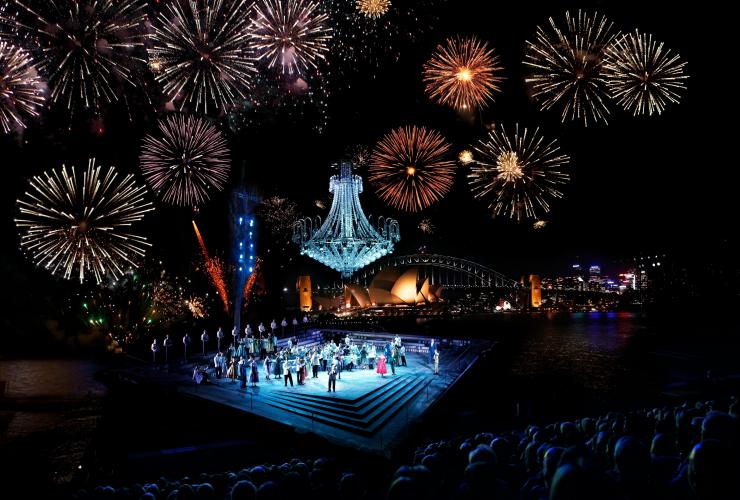 A stage on the banks of the Sydney Harbour with fireworks exploding in the sky at Handa Opera on Sydney Harbour, Sydney, New South Wales © Tourism Australia