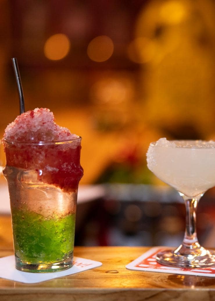 Two cocktails and a side dish lined up along a bar at Cantina OK!, Sydney CBD, New South Wales © Destination NSW