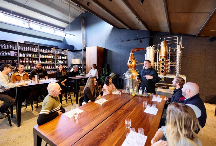 Groups of people seated at large tables while listening to a guide during a gin tasting at Four Pillars Gin, Yarra Valley, Victoria © Tourism Australia
