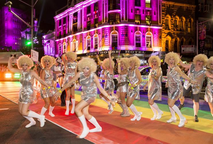 A group of people walking across a rainbow road wearing silver dresses and blonde wigs at Sydney Mardi Gras, Sydney, New South Wales © James Horan/Destination NSW