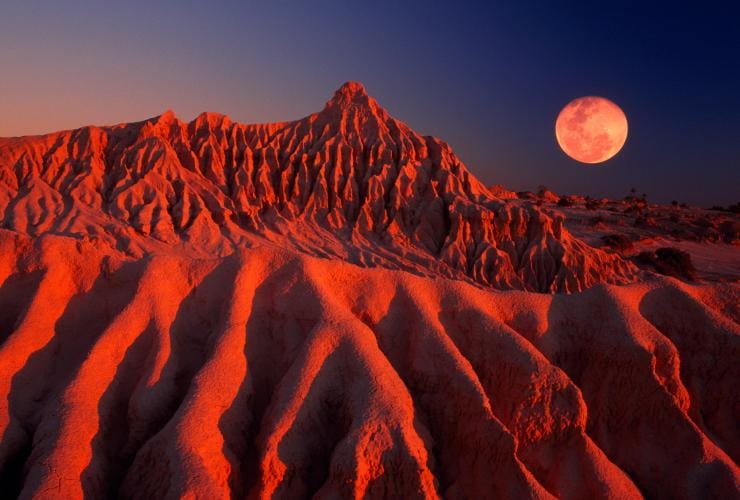 Les formations escarpées de sable et d'argile du Mungo National Park brillant d'un éclat rouge sous la lumière de la pleine lune, Nouvelle-Galles du Sud © Tourism Australia