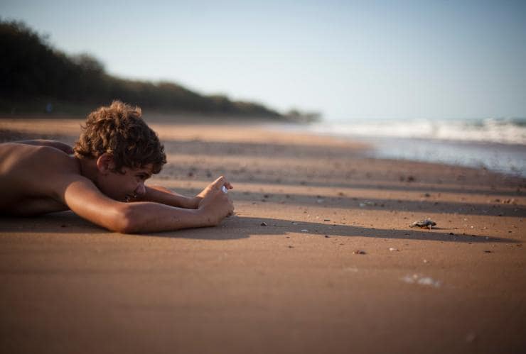 Un garçon photographiant l'éclosion d'une tortue près de l'océan à Mon Repos, sud de la Grande Barrière de Corail, Queensland © Tourism Events Queensland/Rowan Bestman 