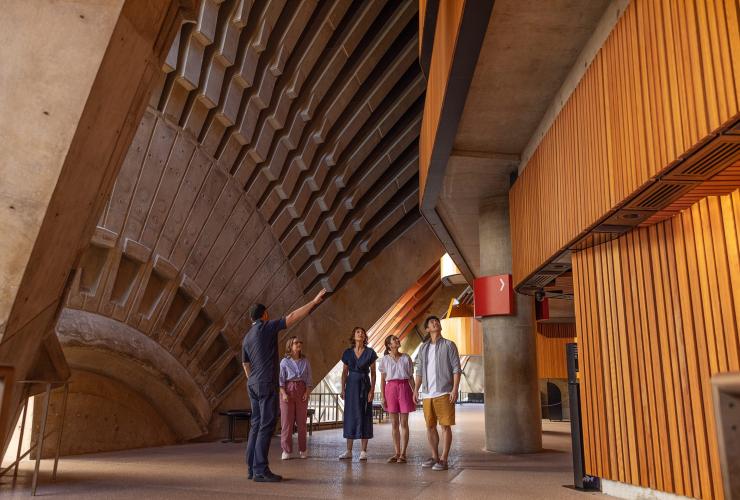 Sekelompok pengunjung mendengarkan pemandu wisata yang menceritakan struktur kompleks Sydney Opera House, Sydney, New South Wales © Tourism Australia