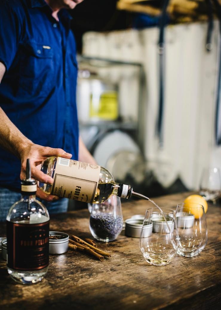 Guida turistica che versa gin in un bicchiere per una degustazione presso la Four Pillars Gin Distillery, Yarra Valley, Victoria © Tourism Australia
