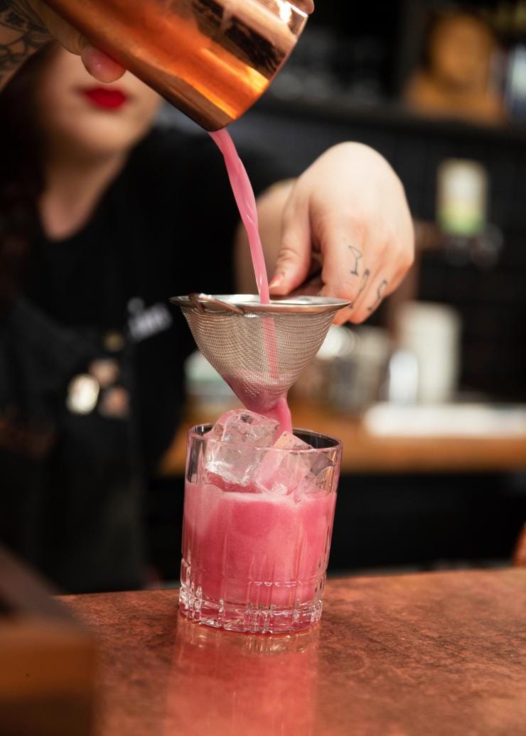 Barista che versa un cocktail color rosa chiaro presso la Four Pillars Gin Distillery, Yarra Valley, Victoria © Visit Victoria