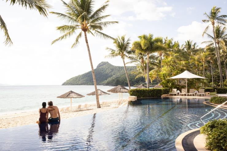一對情侶坐在昆士蘭州聖靈群島漢密爾頓島（Hamilton Island）的無邊際泳池邊眺望海洋©澳洲旅遊局